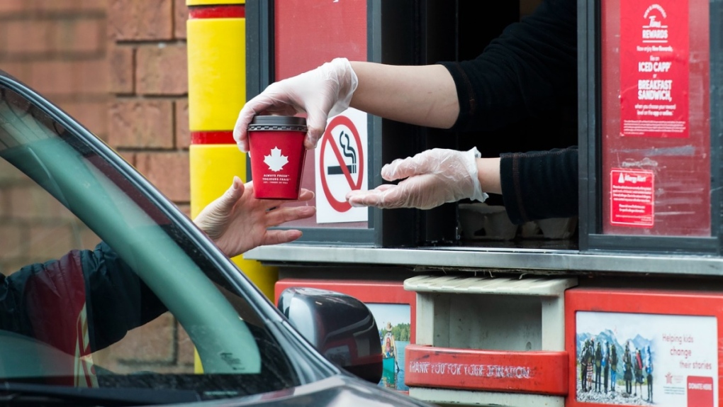 Getting a drink at a Tim Hortons drive-through window in Mississauga, Ont., on March 17, 2020. (Nathan Denette / THE CANADIAN PRESS)