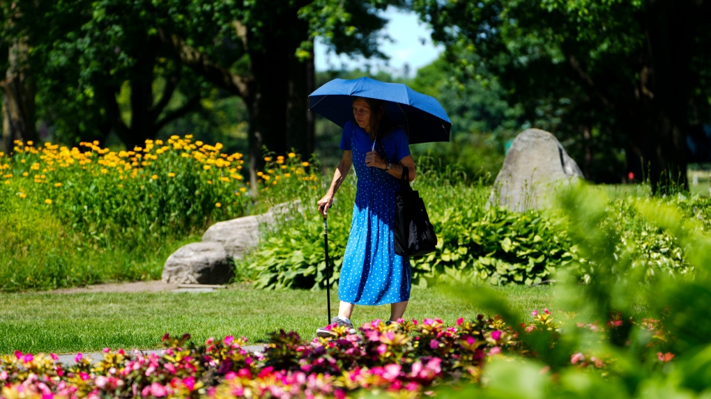 A woman uses an umbrella to shield herself from the sun in Ottawa on Monday, July 4, 2022. THE CANADIAN PRESS/Sean Kilpatrick