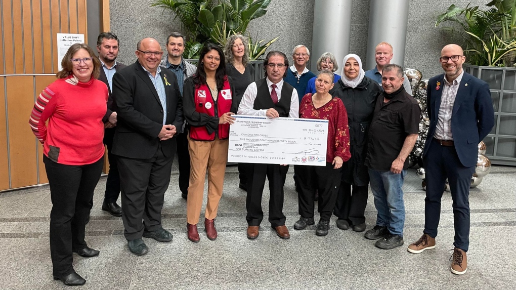 Mo Markham (red shirt, fifth from right) and Sariye Sindy (black coat, fourth from right) present the Red Cross with a cheque for money collected at their fundraising dinner. The cheque presentation took place at Kitchener City Hall on March 25, with several local politicians in attendance. (Karis Mapp/CTV Kitchener)