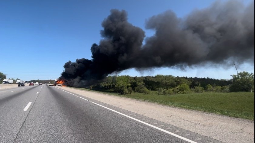 A transport truck is seen on fire along Highway 401 near Guelph with a large plume of black smoke rising into the air. (OPP)